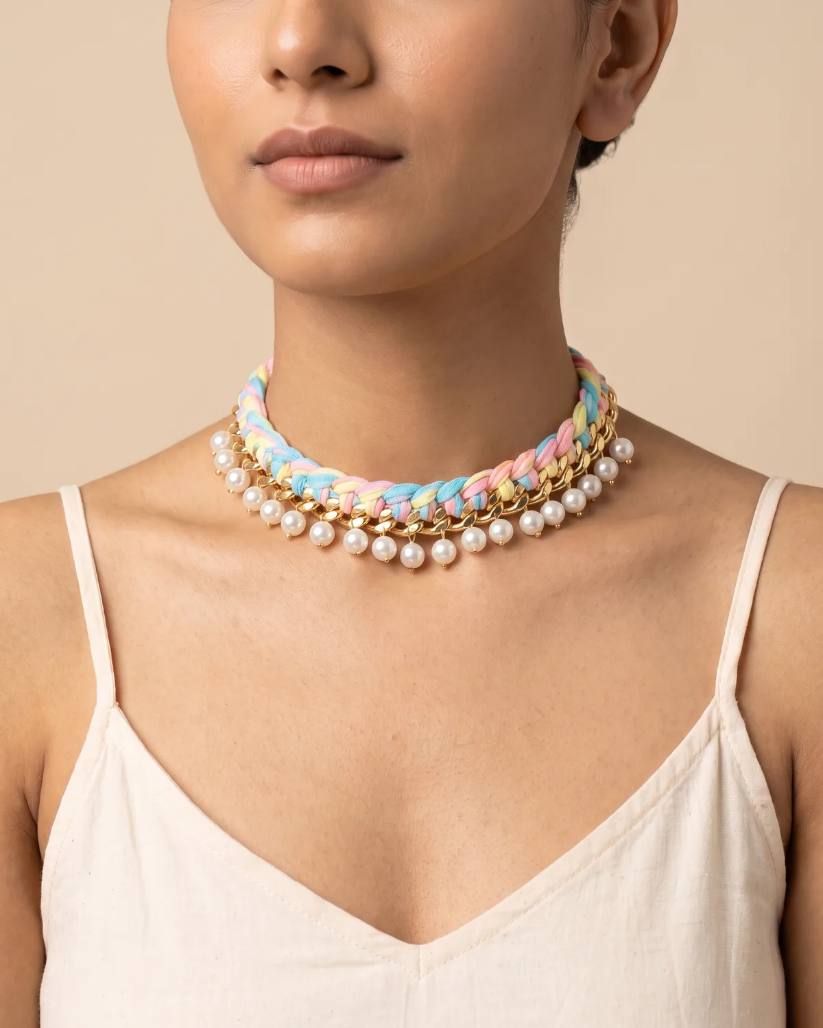 Cotton Candy Choker: a polished gold curb chain intricately braided with pastel pink, blue, and yellow fabric cords and beautifully finished with a fringe of dangling white pearls.