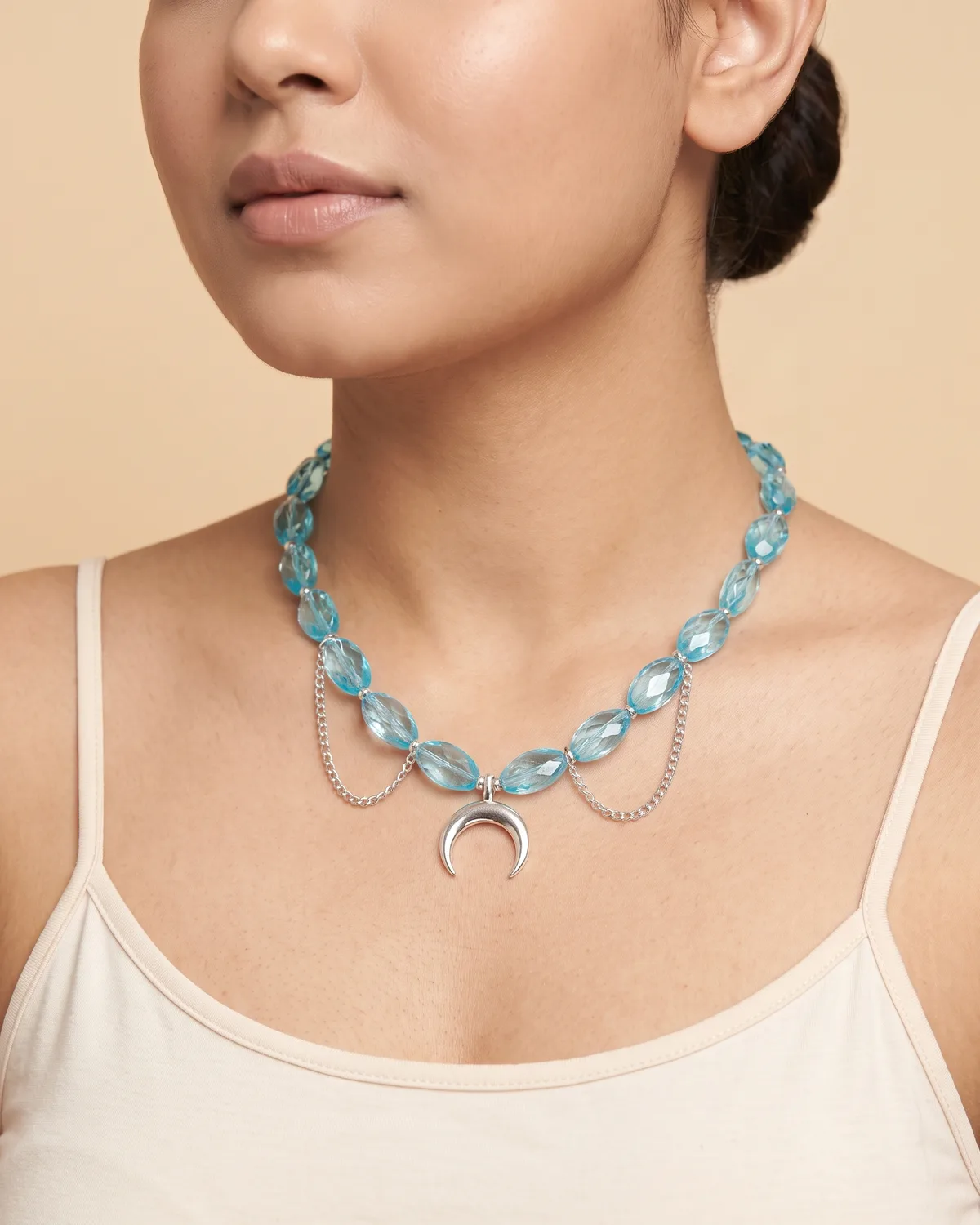 Crescent Wave: a translucent, ice-blue oval crystal beads accented with a polished silver crescent moon pendant and delicate, draped silver side chains.