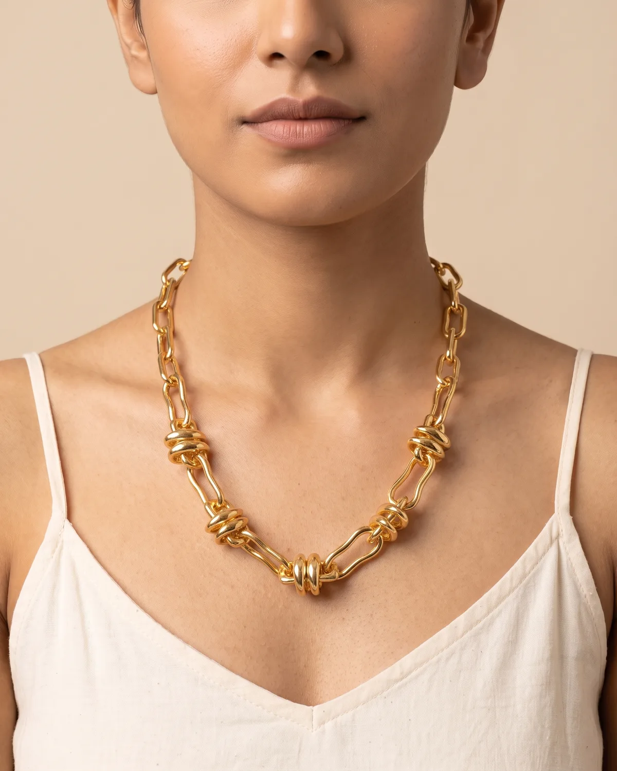 Infinity Link: a chunky, polished gold chain necklace creatively detailed with five evenly spaced decorative knot accents along its lower half.