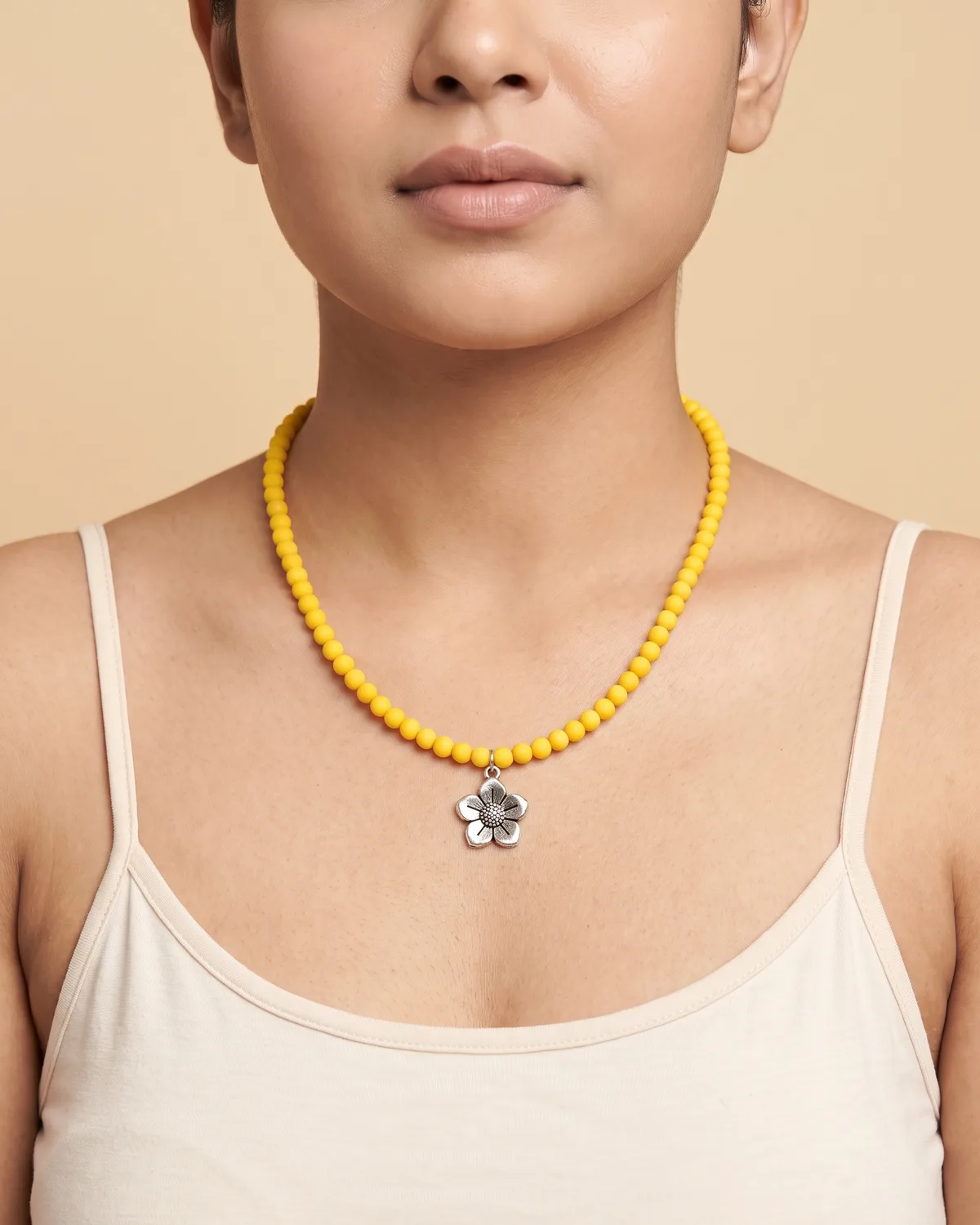 Marigold Meadow: a single strand of small matte yellow round beads accented with a central, antiqued silver flower pendant.
