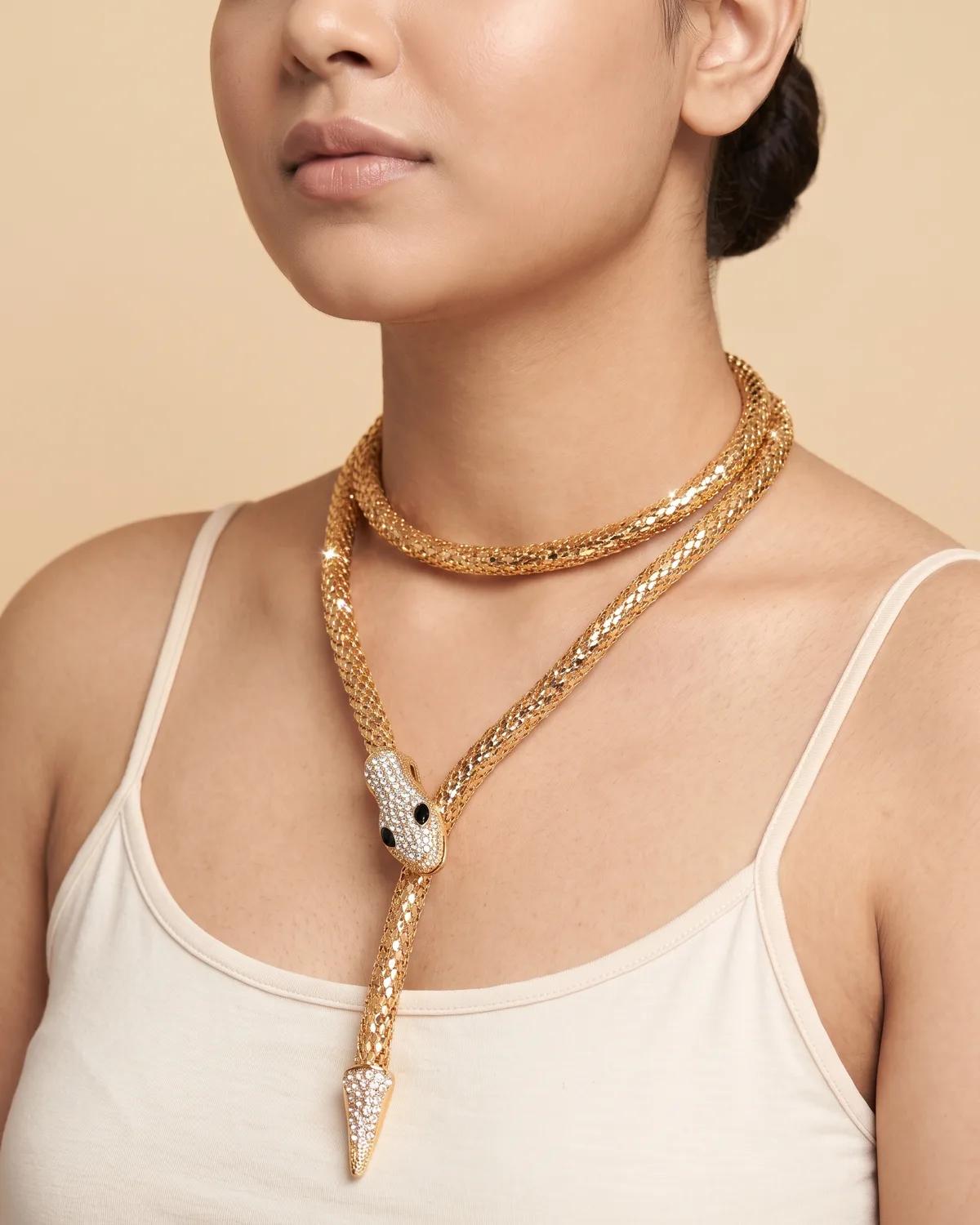 Serpentine Wrap: a long, flexible gold mesh chain sculpted into a multi-layered snake design, complete with a crystal-encrusted serpent head with black stone eyes and a matching crystal-tipped tail.