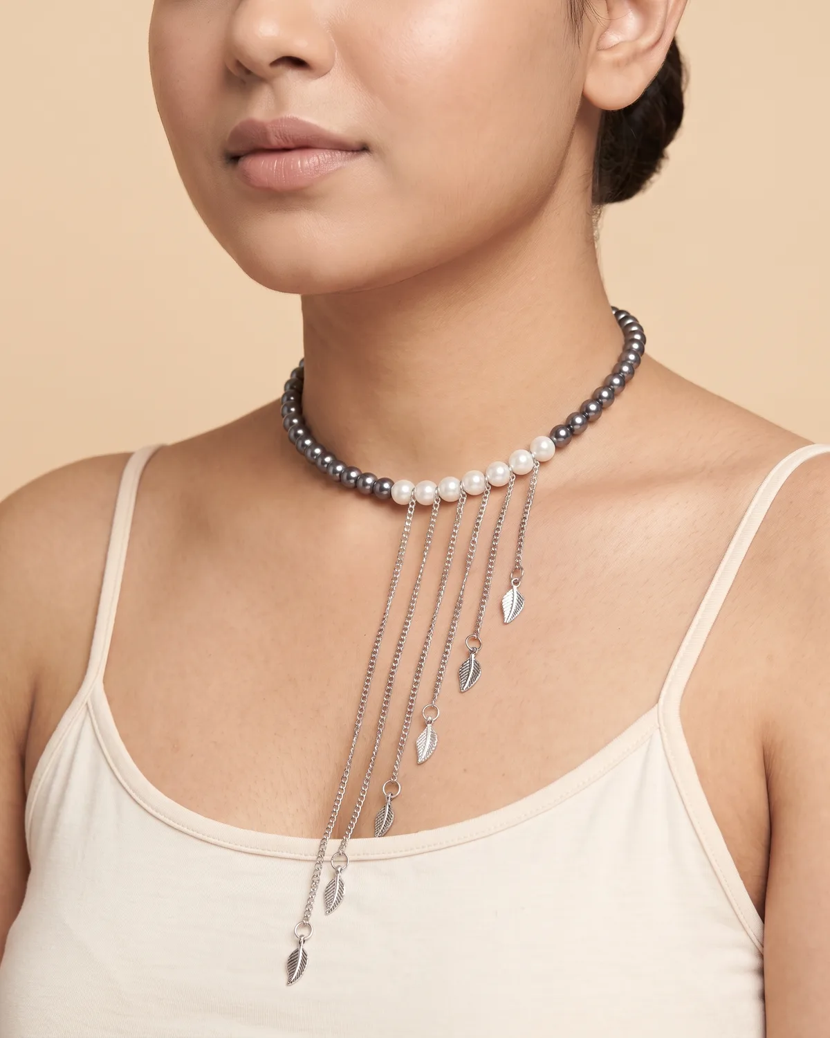 Silver Rainfall Choker: a strand of dark gray pearls with a central accent of white pearls, from which six delicate silver chains of cascading lengths dangle, each finished with a tiny, textured leaf charm.