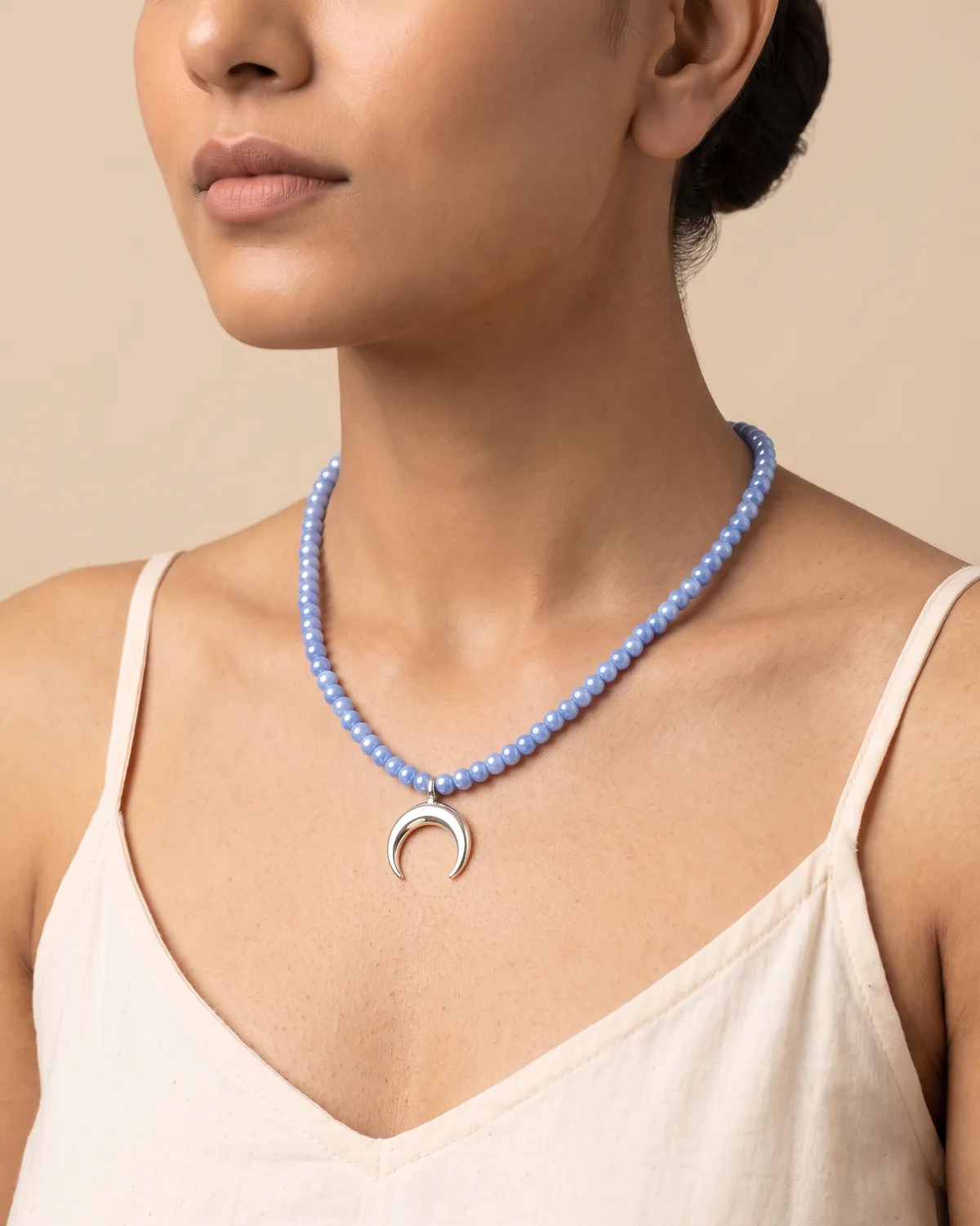 Starlight: a single strand of small, periwinkle-blue round beads accented with a central, polished silver crescent moon pendant.